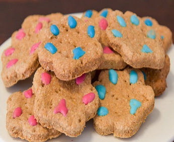 Delicious all-natural paw print dog treats shaped like paw prints with colorful frosting for added fun.